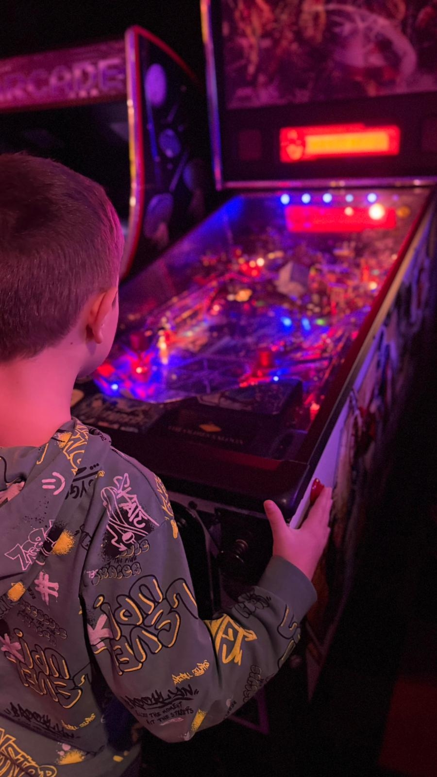 jongen speelt op een flipperkast in de arcade speelhal