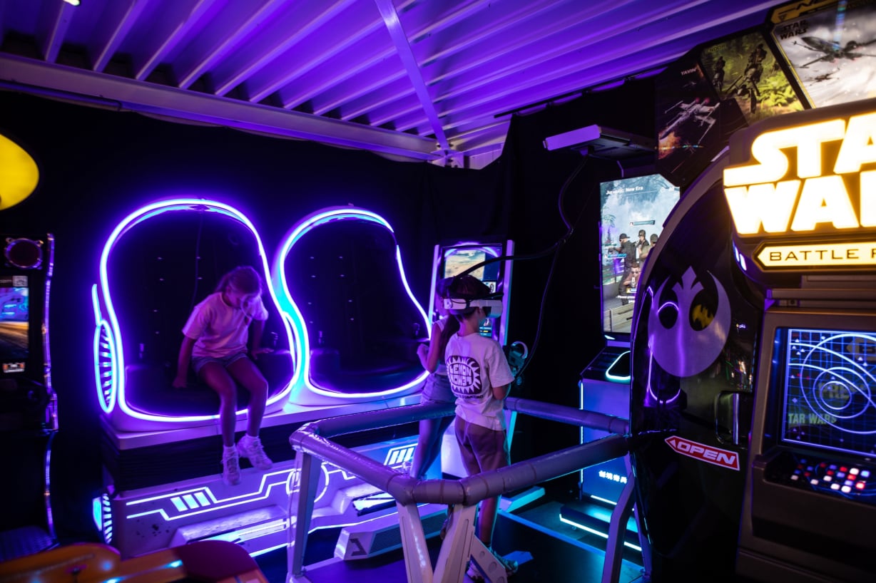 Bezoeker beleeft een VR-ervaring tussen kleurrijke arcadegames