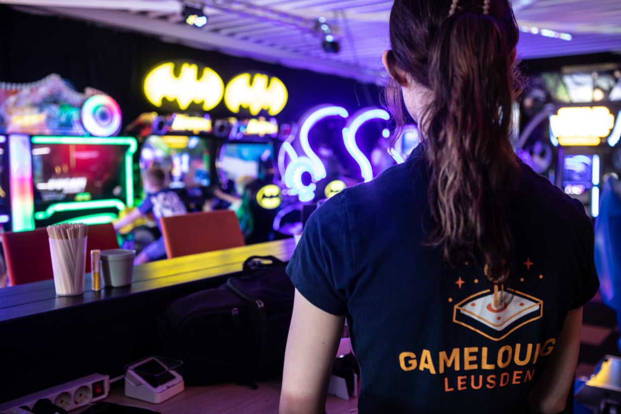 Medewerker staat tussen de arcadekasten in de gamehal.