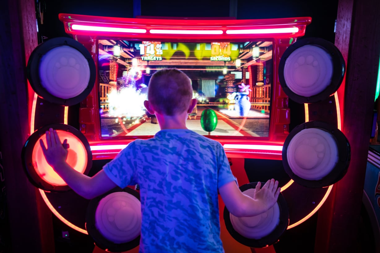 Jongen speelt een interactief arcadespel met grote knoppen. 