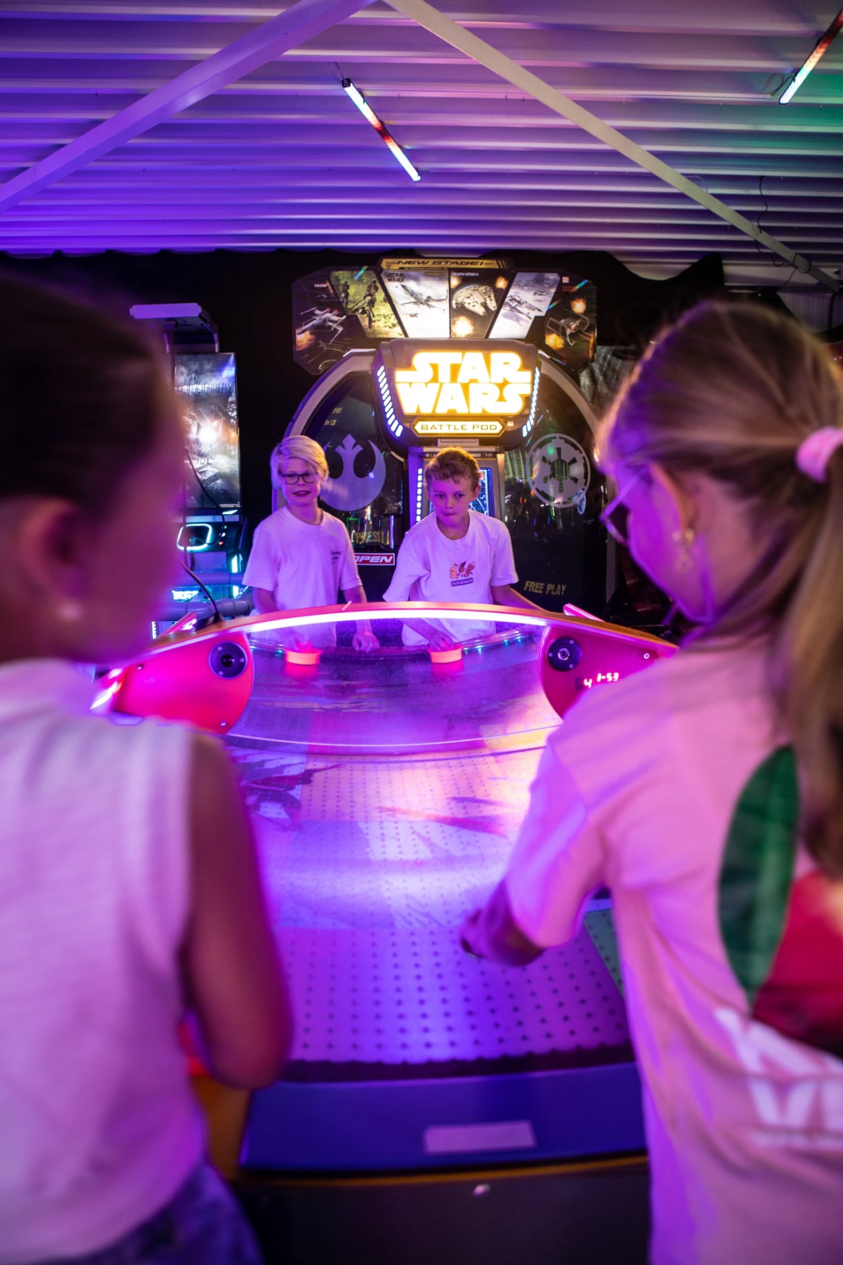 Bezoekers spelen airhockey tussen de arcadekasten in de gamehal. 